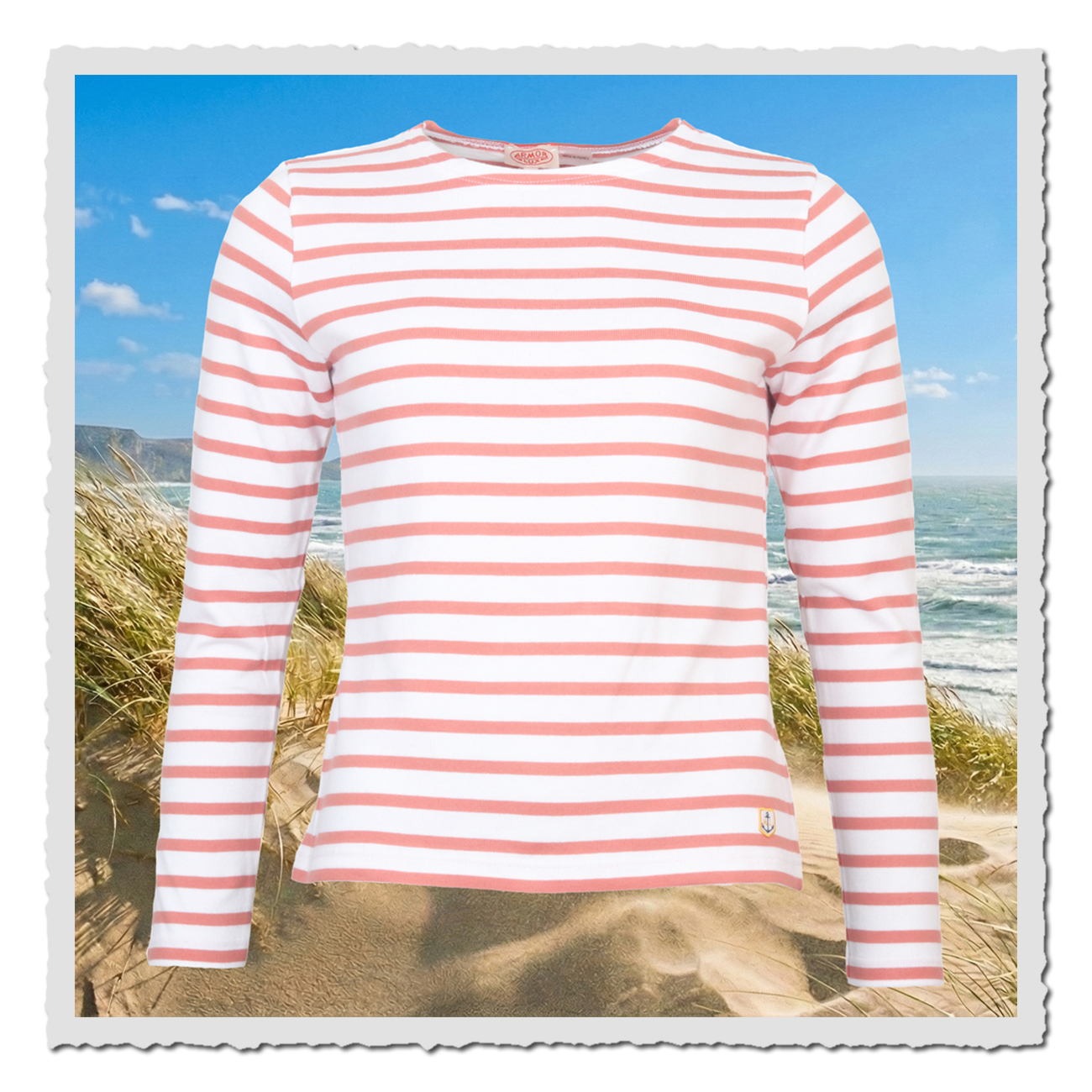 Weiß-rosafarbenes Armor-Lux-Ringelshirt vor maritimer Strandkulisse, klassisches Matrosinnen-Design für entspannte Sommer- und Urlaublooks.